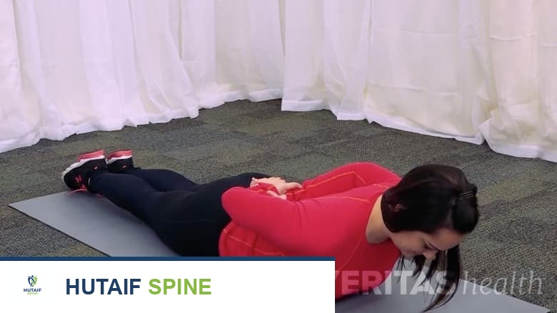 امرأة مستلقية على بطنها تؤدي تمديدًا في وضع الانبطاح.