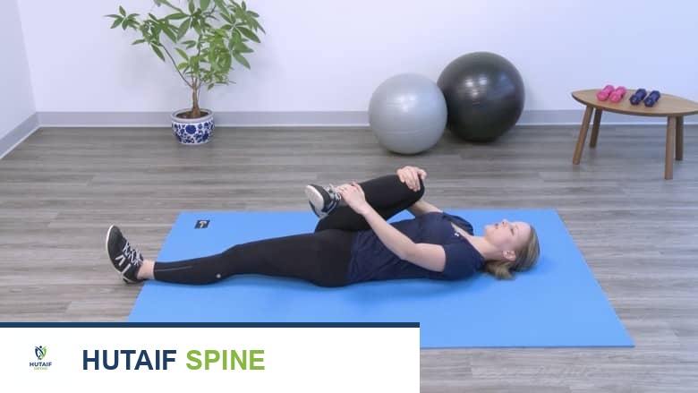 امرأة تؤدي تمرين إطالة العضلة الكمثرية وهي مستلقية على الظهر