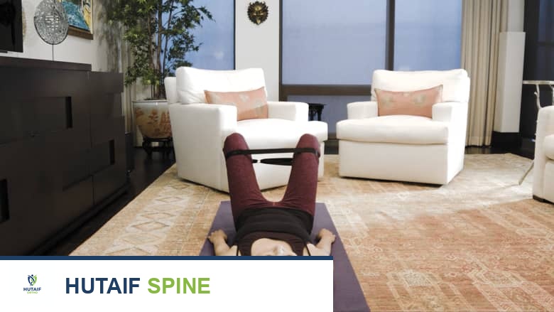 امرأة مستلقية على ظهرها مع حزام مقاومة حول فخذيها، تؤدي تمرين إبعاد الورك أثناء الاستلقاء على سجادة اليوغا.