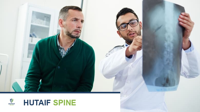 Doctor pointing to an X-ray scan, sitting next to a patient.